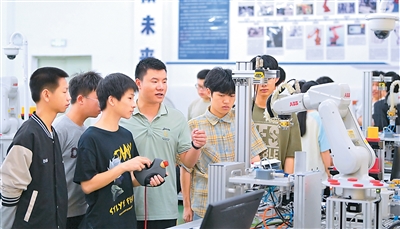 江西省瑞金市瑞金中等专业学校工业机器人实训基地，老师在指导学生在操作智能机械臂。 新华社发